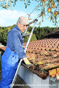 Handwerker reinigt die Dachrinnen eines Hauses