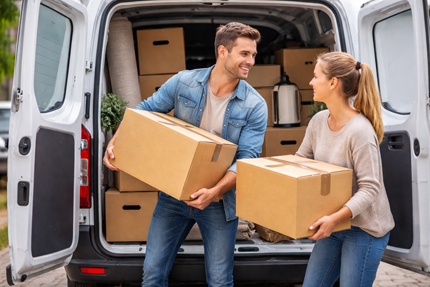 Ein Pärchen räumt Umzugskartons in einen Transportwagen